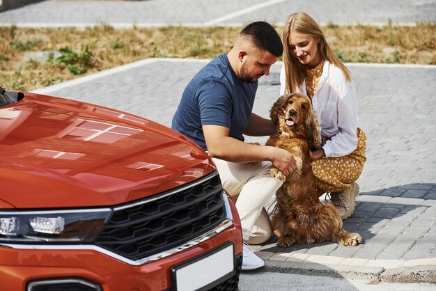 Foto se sienta con la mascota. una pareja encantadora da un paseo junto con un perro al aire libre cerca del camión.