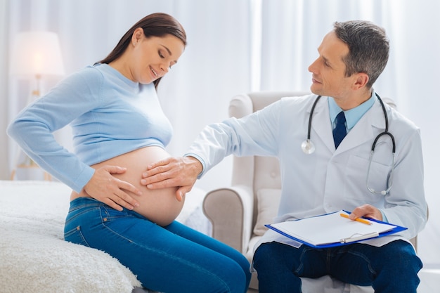 Siente movimientos. Morena atenta manteniendo una sonrisa en su rostro e inclinando la cabeza mientras mira su barriga