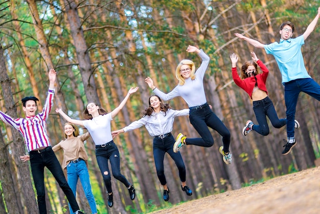 Siete divertidos adolescentes saltando de 1519 años en el bosque de verano