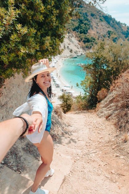 Siga-me a mulher do conceito puxando o homem para a praia do mar