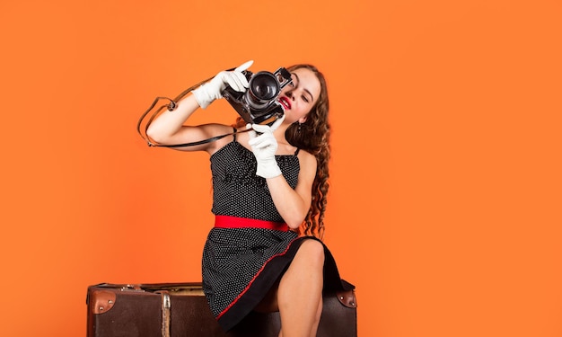 Siga su sueño Accesorios para vacaciones Capturando recuerdos de vacaciones Linda chica lista para viajar Servicio de seguros Tomando fotos de vacaciones Niño pequeño sentado en una maleta vintage con cámara retro