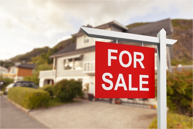 Foto signo de bienes raíces frente a casa nueva en venta