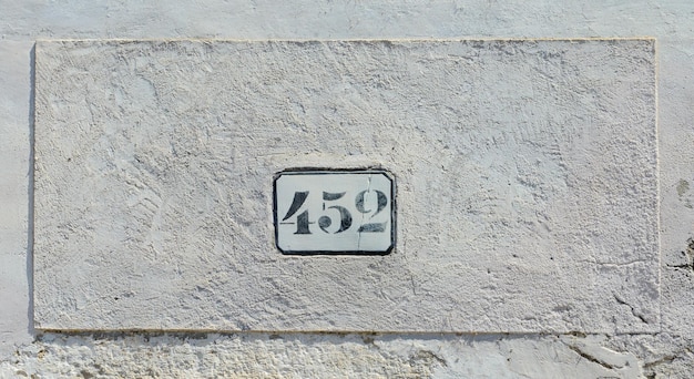 Signo de casa número 452 a la vieja pared blanca