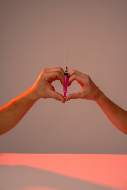 Foto signo de corazón con jeringa rosa aislado sobre pared gris