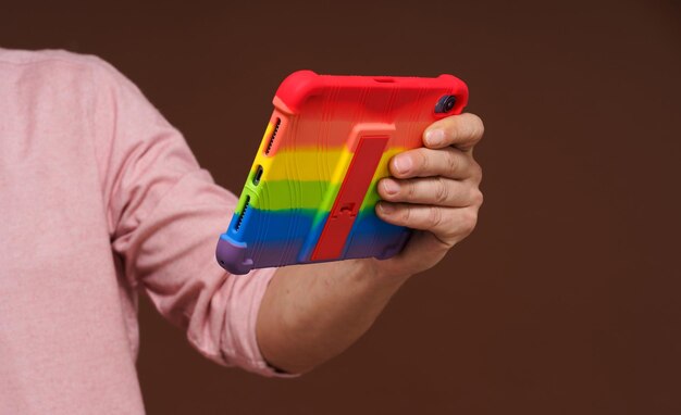 Signo de cultura gay y orgullo lgbtq que representa la mano del hombre sosteniendo una computadora de bolsillo adornada con un arco iris