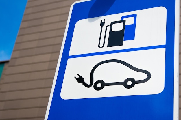 Signo de estación de carga de coches eléctricos frente a un estacionamiento público en la ciudad
