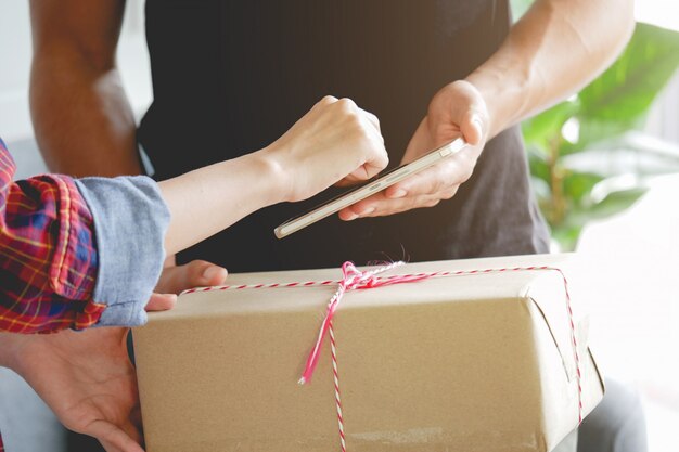 Signo de firma de anexión de mujer en el teléfono inteligente después de recibir cajas de shoppin hombre de entrega