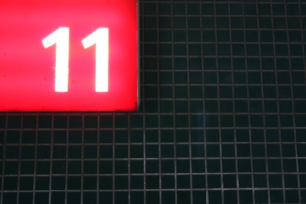 Signo iluminado número 11 en la pared de azulejos