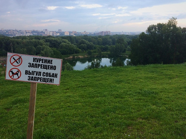 Foto signo de información en el campo por árboles contra el cielo