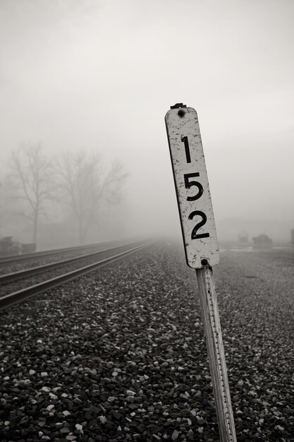 Foto signo de información en la vía ferroviaria contra el cielo durante el tiempo de niebla