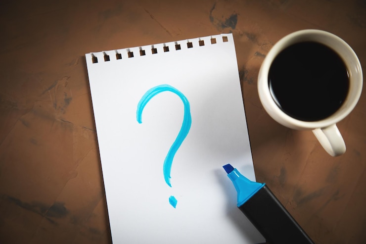 Foto signo de interrogación en el bloc de notas con taza de café en la mesa