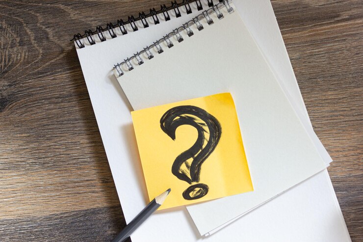 Foto signo de interrogación del concepto de idea en una hoja de papel con blocs de notas y un lápiz en una mesa de madera