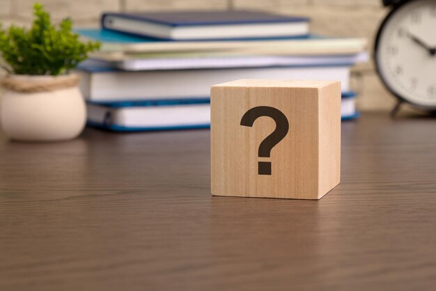 Signo de interrogación escrito en un cubo de madera sobre una mesa de negocios y educación.