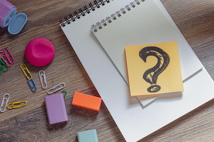Foto signo de interrogación de escritorio creativo en borradores de clips de papel de bloc de notas y sacapuntas