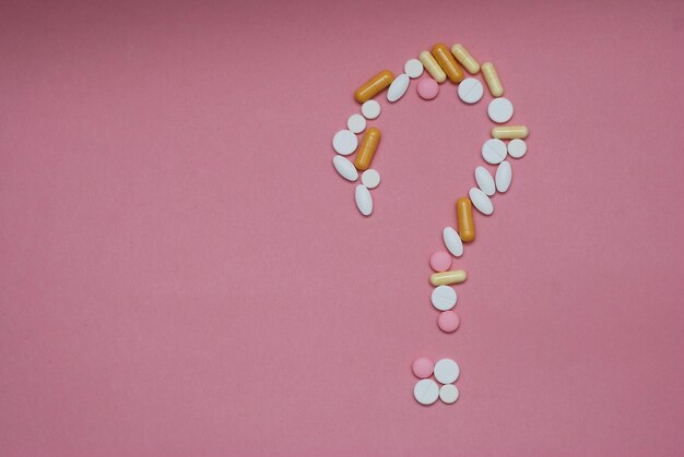 Signo de interrogación de pastillas sobre fondo rosa. Medicina creativa para problemas médicos de salud, interacción farmacológica, error de medicación y concepto farmacéutico.