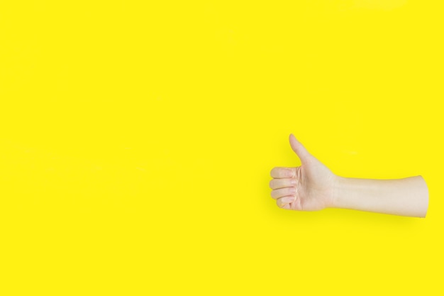 Signo de mano pulgar hacia arriba con espacio de copia sobre fondo amarillo.