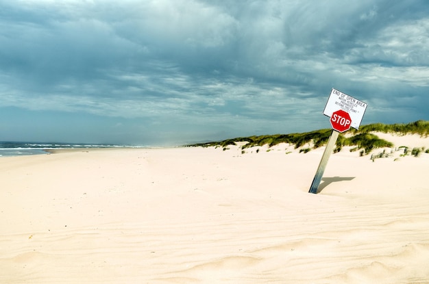 Foto signo de parada en la arena en la playa contra el cielo nublado