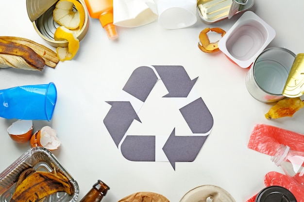 Signo de reciclaje y basura sobre fondo blanco.
