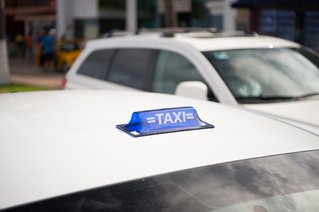 Signo de taxi en el techo de la cabina blanca sobre fondo de paisaje urbano. Vehículo de alquiler, servicio de transporte, transporte, concepto de viaje.