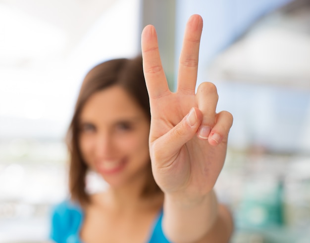 Foto signo de voctory de mujer joven contra fondo de empresa