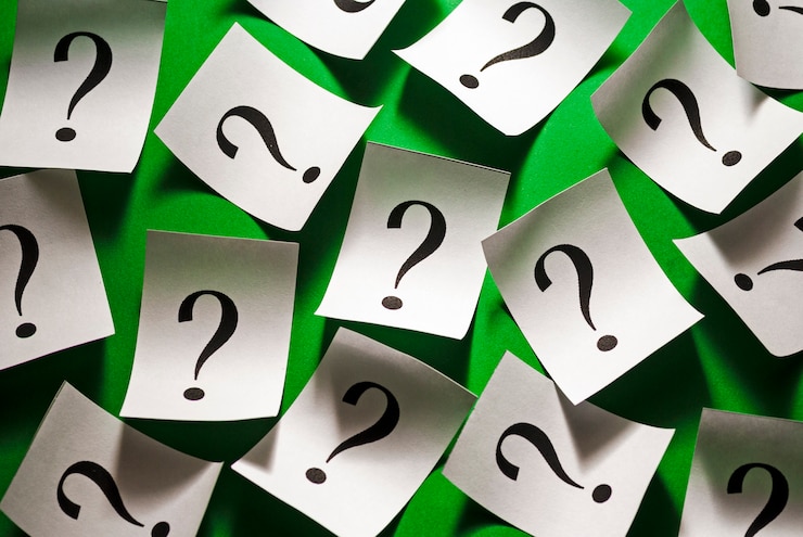 Foto signos de interrogación dispersos al azar en papel blanco
