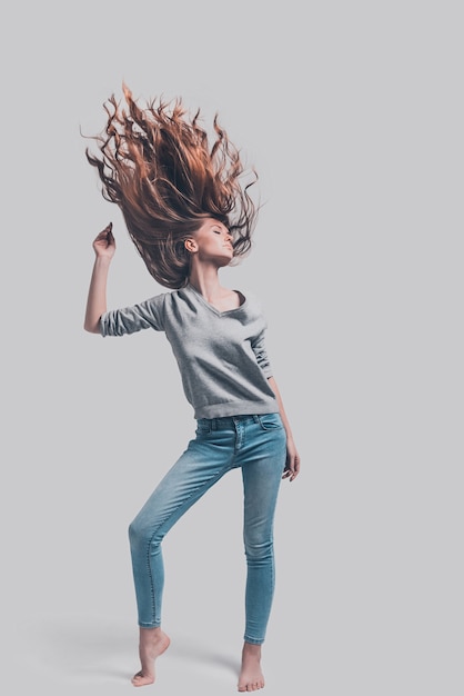 ¡Sigue moviendote! Disparo de estudio de longitud completa de mujer joven atractiva con el pelo revuelto posando