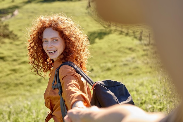 Sígueme atractiva mujer rizada toma la mano del hombre lleva en el bosque para caminar, viajar, sonriendo felizmente ...