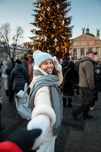 Sígueme concepto mujer tirando de hombre al árbol de navidad