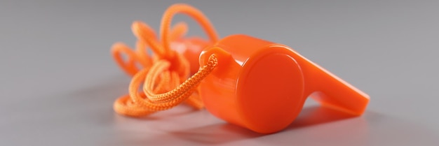 Silbato deportivo naranja sobre herramienta de superficie gris para entrenadores escolares
