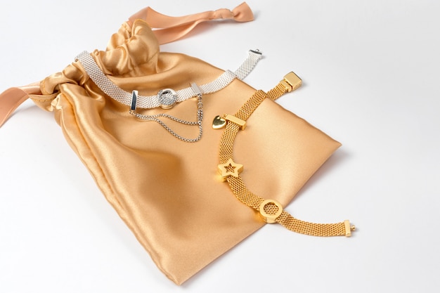 Silber- und Goldarmbänder in einer goldenen Seidengeschenktüte
