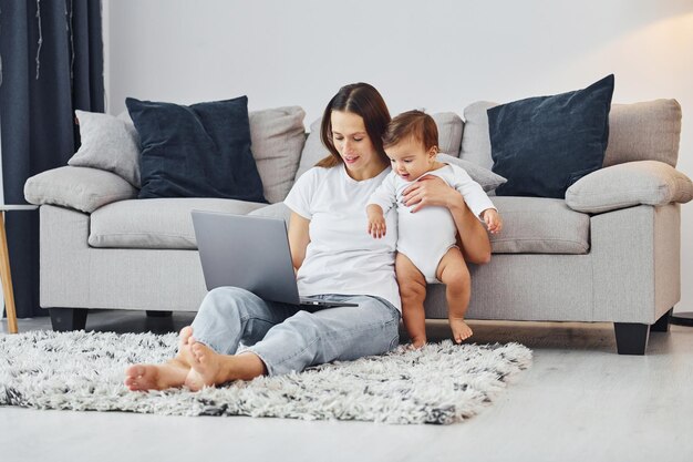 Silberfarbener Laptop Mutter mit ihrer kleinen Tochter ist zusammen zuhause zu Hause