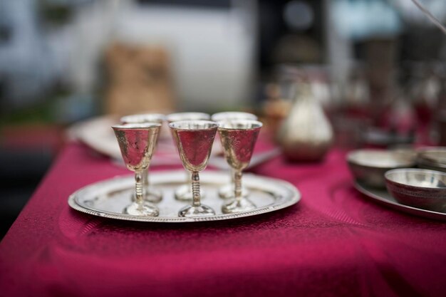 silberne Gläser auf einem silbernen Teller auf dem Tisch rote Tischdecke