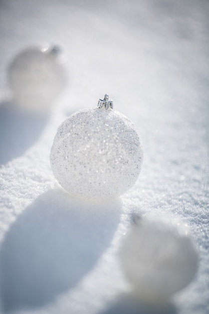 Silberne Weihnachtskugeln auf echtem Schnee im Freien. Winterurlaub Konzept. Geringe Schärfentiefe