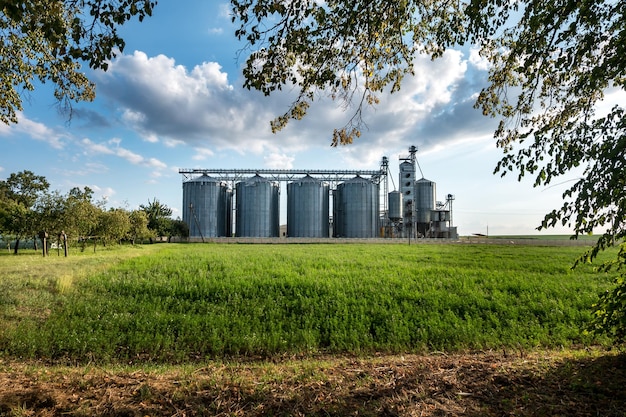 Foto silbersilos auf agro-produktionsanlagen zur verarbeitung, trocknung, reinigung und lagerung von landwirtschaftlichen produkten, mehl, getreide und getreide mit schönen wolken