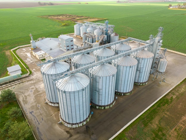 Silbersilos auf einer Agro-Produktionsanlage zur Verarbeitung, Trocknung, Reinigung und Lagerung von landwirtschaftlichen Produkten, Mehl, Getreide und Getreide Fliegen einer Drohne über Eisenfässern mit Getreide-Quadcopter-Foto