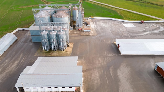 Silbersilos auf einer Agro-Produktionsanlage zur Verarbeitung, Trocknung, Reinigung und Lagerung von landwirtschaftlichen Produkten, Mehl, Getreide und Getreide Fliegen einer Drohne über Eisenfässern mit Getreide-Quadcopter-Foto