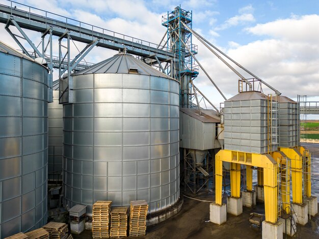 Silbersilos auf einer Agro-Produktionsanlage zur Verarbeitung, Trocknung, Reinigung und Lagerung von landwirtschaftlichen Produkten, Mehl, Getreide und Getreide Fliegen einer Drohne über Eisenfässern mit Getreide-Quadcopter-Foto