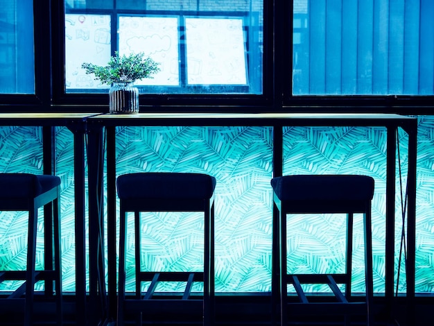 Silhouette Barhocker und Holztheke in der Nähe des Fensterglases im Blaulichtraum