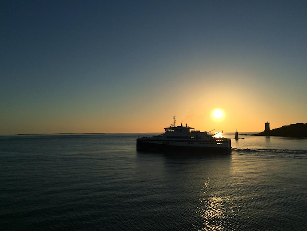 Silhouette-Boot, das während des Sonnenuntergangs auf einem klaren Himmel auf dem Meer segelt