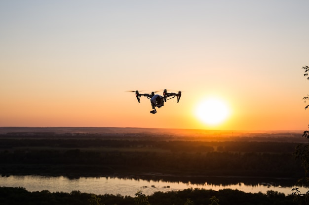 Silhouette der Drohne, Quadrocopter mit Fotokamera, die in den Himmel fliegt.