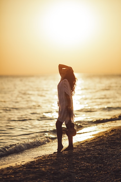 Silhouette der Frau mit Ukulele auf den Strandsommerferien