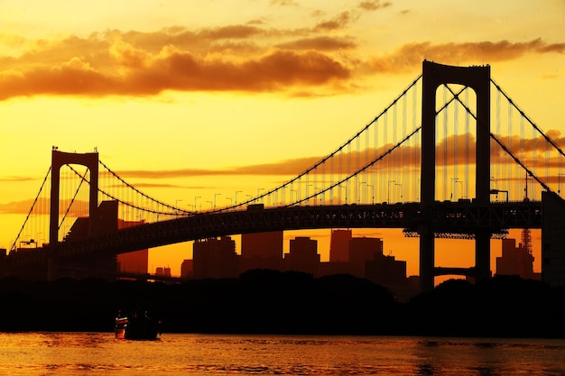 Silhouette der Hängebrücke über dem Fluss beim Sonnenuntergang