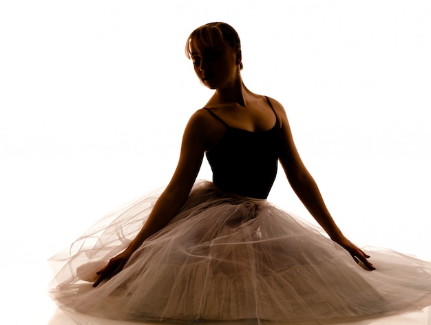Silhouette der jungen schönen Ballerina im weißen Tutu und in den Spitzenschuhen, die tanzende Pose tun