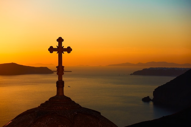 Silhouette der Kuppel mit Kreuz der griechisch-orthodoxen Kirche und dem Meer im Hintergrund nach Sonnenuntergang. Stadt Fira, Santorini, Griechenland. Landschaft