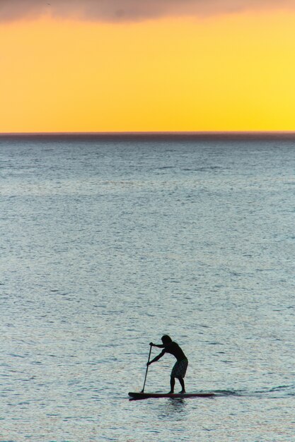 Silhouette des Mannes mit seinem Stand-Up-Paddel mit einem schönen Sonnenuntergang