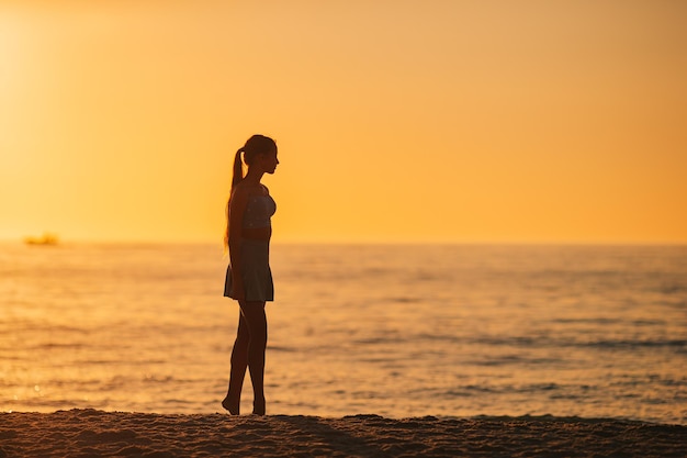 Silhouette des schönen Mädchens, das einen wunderschönen Sonnenuntergang am Strand genießt