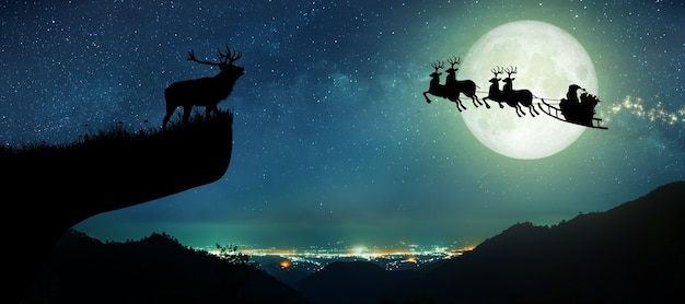 Silhouette des weihnachtsmannes, der nachts auf seinem rentier über den vollmond fliegt weihnachten