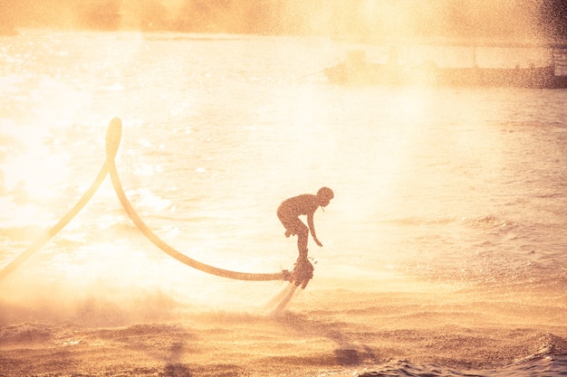 Silhouette e estilo de cor do vintage que mostra o flyboard no rio Chaophya