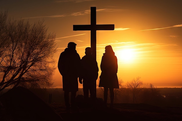 Silhouette einer Familie, die bei Sonnenuntergang ein Kreuz bewundert