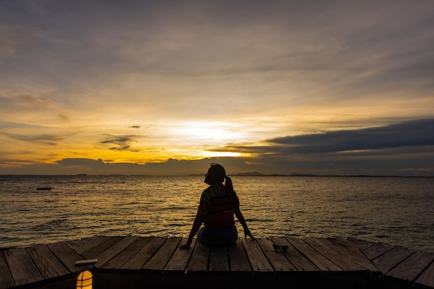 Silhouette einer Frau, die bei Sonnenuntergang auf dem Meer springt, weicher Fokus und zurückhaltend